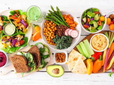 Salater, grønnsaker, frukt, grønn smoothie og grovt brød på et bord. Bildet viser sunn mat. Foto