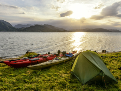 Kajakker og telt ved en fjord. Foto