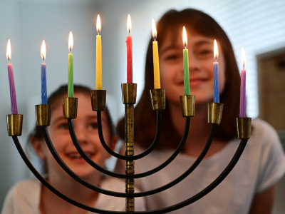 To barn som har tent lysene i en lysestake som blir brukt under den jødiske lysfesten hanukka. Foto.